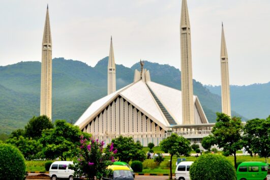 Faisal Mosque in Islamabad with lush green Margalla Hills in the background.