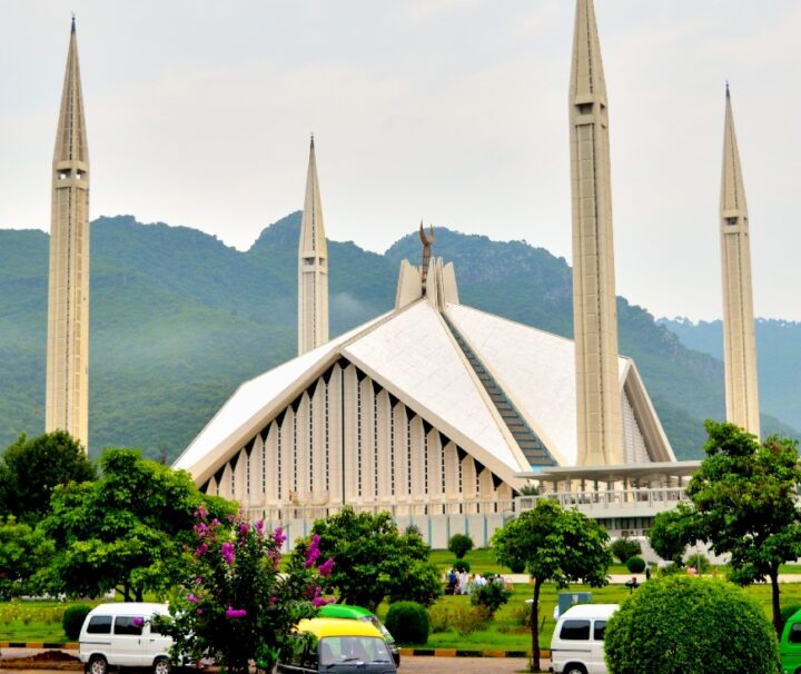 Faisal Mosque in Islamabad with lush green Margalla Hills in the background.