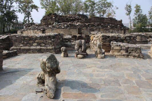 Ruins of an ancient Buddhist site in the Gandhara region, featuring weathered stone structures and remnants of sculptures.