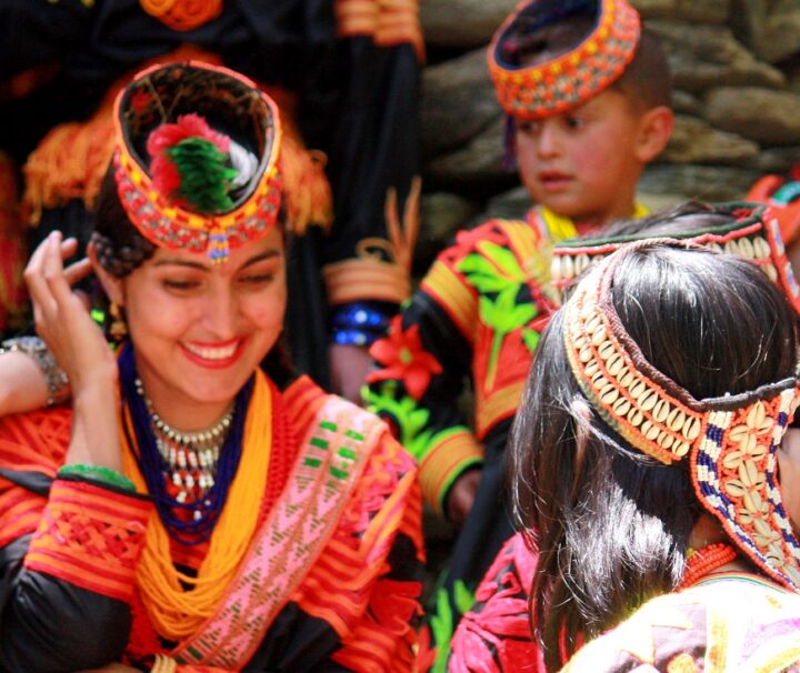 Kalash women and children dressed in traditional attire, celebrating a cultural festival in Pakistan.